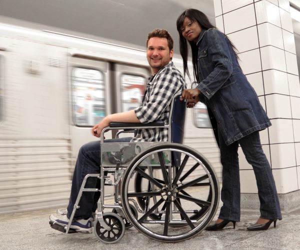 Young woman pushing wheelchair for a disabled man